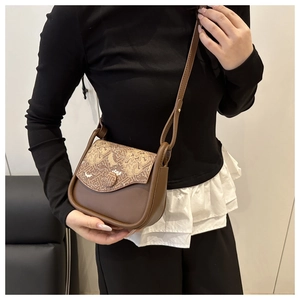Detail of vintage patterned flap on brown crossbody bag with adjustable shoulder strap
