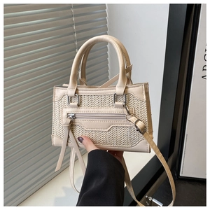 Dettaglio borsa a tracolla intrecciata beige con finiture in pelle e nappine lunghe