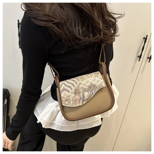 Detailed side view of brown leather bag with wave embroidery and adjustable strap