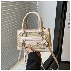 Dettaglio borsa in paglia intrecciata con finiture in pelle beige e tracolla rimovibile