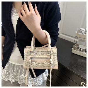 Détail d'un mini sac bandoulière tissé avec pompons en cuir et deux poignées