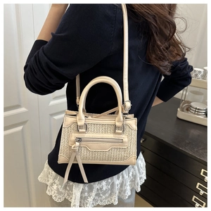 Dettaglio della borsa a tracolla intrecciata beige con finiture in pelle e nappa decorativa