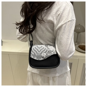 Close-up of Chinese style crossbody bag with white jacquard pattern on matte black leather