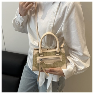 Détail d'un sac à bandoulière en paille tissée beige avec glands et garniture cuir