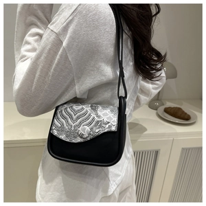 Detailed embroidery on black leather crossbody bag featuring traditional wave patterns