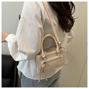 Détail du sac bandoulière tissé beige avec texture en losange et long gland élégant