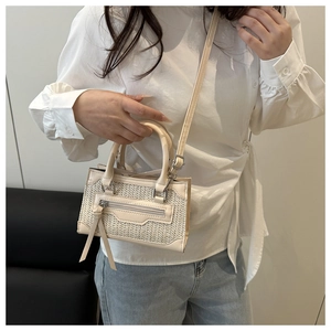 Détail d'un mini sac à main en paille et cuir avec franges porté par un mannequin