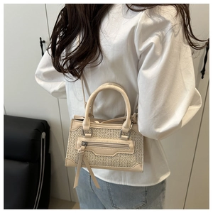 Détail d'un mini sac bandoulière beige tissé avec poignée en cuir et longues franges