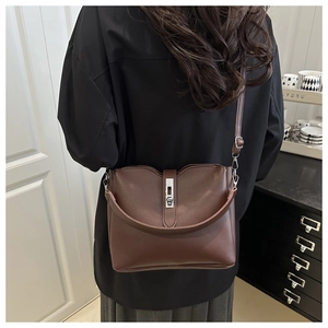 Sac seau en cuir marron avec bord ondulé et fermoir métal porté à l'épaule de dos