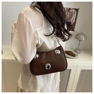 Detail of dark brown leather underarm bag featuring large silver metal studs and chain strap