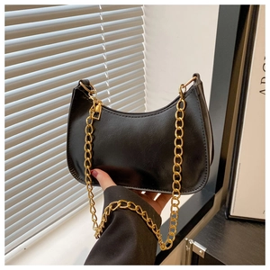 Detail of black faux leather crescent bag with chunky gold chain strap and metal rings