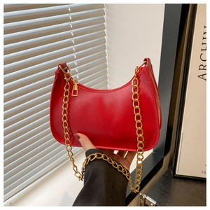 Model holding a vibrant red crescent shoulder bag with golden metal chain details