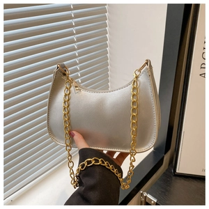 Close-up of a silver crescent-shaped bag with a bold gold chain and leather texture