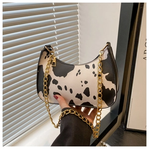 Detail of hobo bag with cow print pattern and elegant golden metal chain strap