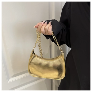 Detail of a shiny gold metallic shoulder bag with golden chain strap and smooth texture