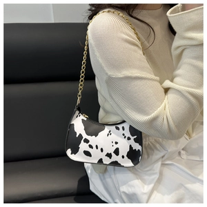 Close-up of cow print underarm bag featuring premium gold chain strap on shoulder