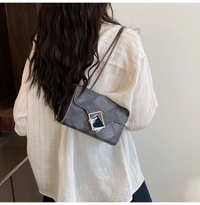 Gros plan d'un sac bandoulière gris foncé matelassé avec une boucle carrée dorée