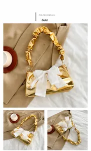 Detail der goldene Baguette-Tasche mit weißer Schleife und gerafftem Griff
