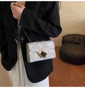 Détail du sac bandoulière gris matelassé avec boucle géométrique et chaîne fine