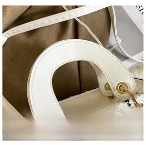Dettaglio di una borsa chic in tweed intrecciato con manici in pelle bianca e anelli oro