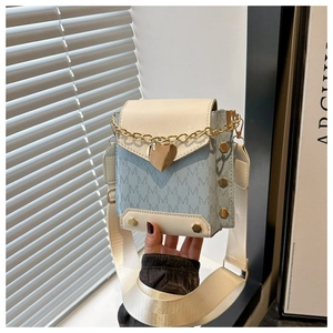 Detalle de mini bolso bandolera azul y blanco con cadena de corazón dorada y patrón M