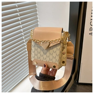 Detalle de bolso bandolera beige con colgante de corazón y monograma