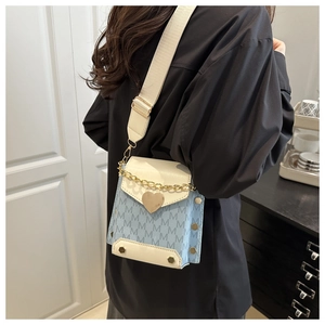 Detalle de bolso bandolera azul y blanco con cierre de corazón y correa en modelo