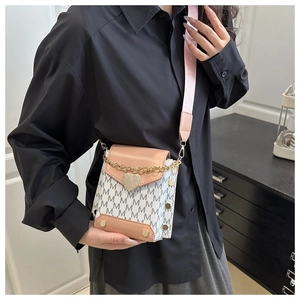 Detailed close-up of textured monogram shoulder bag with gold heart clasp and pink strap