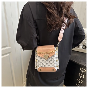 Detail view of stylish crossbody bag with gold heart clasp and pink wide fabric strap