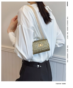 Détail d'un sac à paillettes dorées avec chaîne et fermoir porté par un mannequin