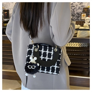 Dettaglio borsa a mano in tweed bianco e nero con ciondolo soffice e tracolla fine