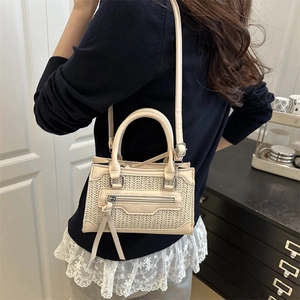 Sac bandoulière tressé crème avec glands en cuir et bandoulière réglable porté par un mannequin