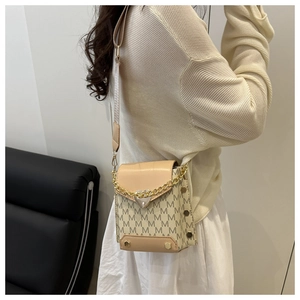 Detalle del bolso bandolera beige con estampado M y colgante de corazón dorado en modelo