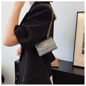 Détail du mini sac à paillettes argentées avec chaîne dorée sur veste noire