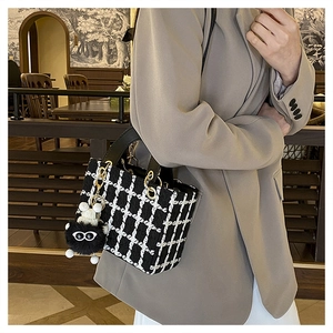 Dettaglio della borsa in tweed bianco e nero con finiture dorate e ciondolo di peluche