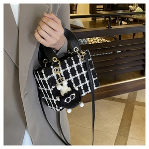 Dettaglio borsa in tweed pied-de-poule con manico in pelle e charm mostriciattolo
