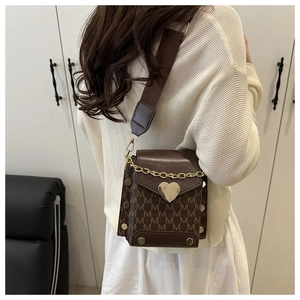 Detail view of heart-shaped gold clasp and M-letter print on canvas crossbody bag