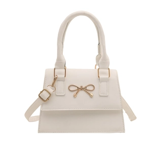 White faux leather top-handle bag with gold bow ornament and adjustable shoulder strap