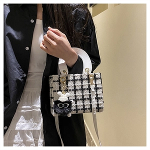 Dettaglio della borsa in tweed bianco e nero con ciondolo a mostriciattolo peloso
