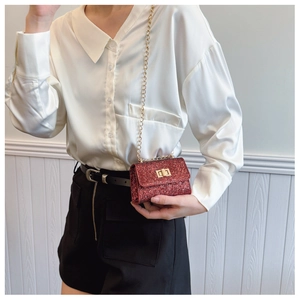 Détail du mini sac bandoulière à paillettes rouges avec chaîne dorée et fermoir rotatif