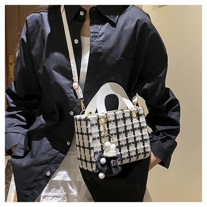 Dettaglio di una mini borsa a tracolla in tweed con bordi a contrasto e ciondolo a pompon