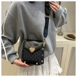 Detail of black crossbody bag with heart pendant and adjustable wide shoulder strap