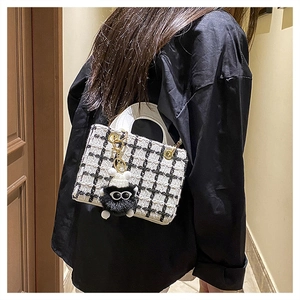 Vista dettagliata della borsa a tracolla in tweed bianco e nero con ciondolo a mostro