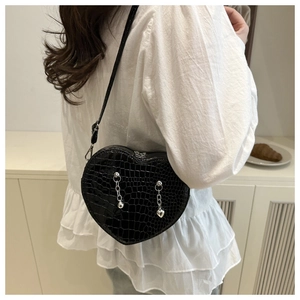 Detail of black heart-shaped handbag with crocodile texture and silver metal chains