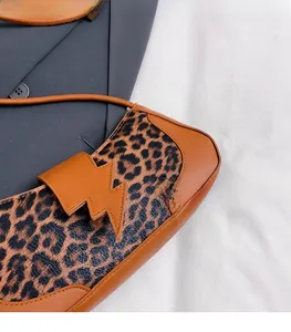 Détail du sac à main léopard avec bordure en cuir marron et rabat au design éclair moderne