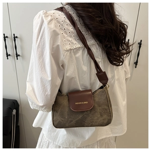 Dettaglio della borsa sottobraccio vintage in tela con patta in pelle e scritte