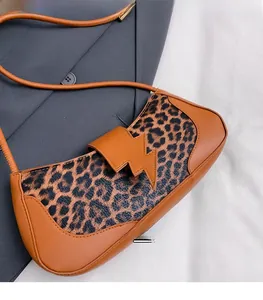 Détail du sac à bandoulière léopard avec bordure orange et boucle en forme d'éclair