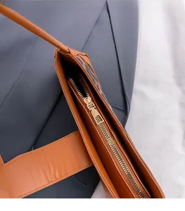 Détail de la fermeture éclair dorée et du cuir marron sur un sac à bandoulière
