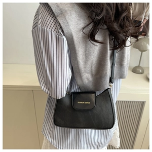 Dettaglio della borsa sottobraccio in pelle nera opaca con logo dorato e chiusura magnetica