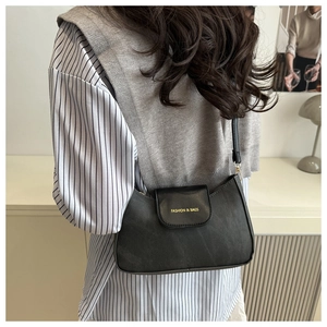 Rear view of a model wearing a black retro shoulder bag with gold printed fashion slogan